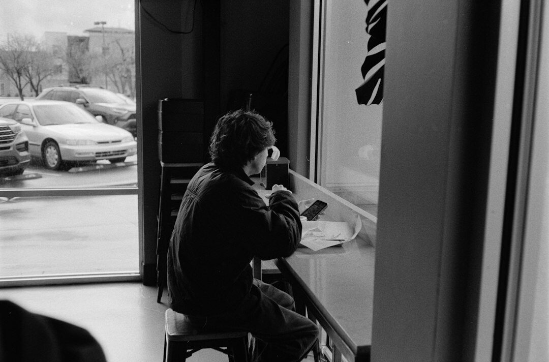 Person writing in a notebook by a cafe window